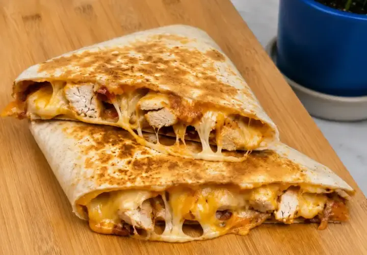 Pyszna quesadilla z kurczakiem, z ciągnącym się serem i kawałkami soczystego mięsa, podana na drewnianej desce.