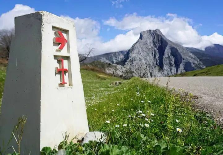 Señal del camino lebaniego, indicando la ruta. El paisaje montañoso sugiere la dificultad del camino.