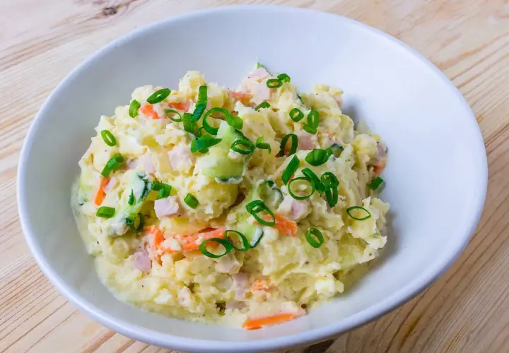 En skål med krämig potatissallad, toppad med purjolök. Den här ser ut att vara den godaste potatissalladen!