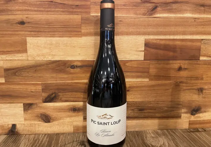 Bouteille de vin rouge du domaine Pic Saint Loup, "Réserve Les Almadies", sur fond de bois.
