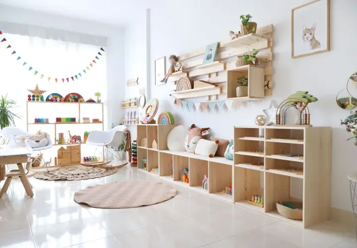 Acogedor rincón de juegos en el salón, con estanterías de madera llenas de juguetes educativos, cojines y una alfombra circular.