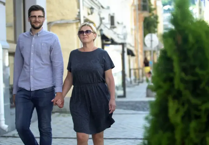 Para spaceruje ulicą, trzymając się za ręce. Młodszy mężczyzna w okularach i starsza kobieta pokazują, że różnica wieku w związku nie jest przeszkodą.