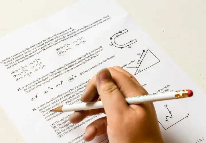 Dłoń z ołówkiem rozwiązuje test z fizyki. Pytanie 22 dotyczy satelitów, a od jakiej średniej jest 5? Odpowiedź D jest zaznaczona.