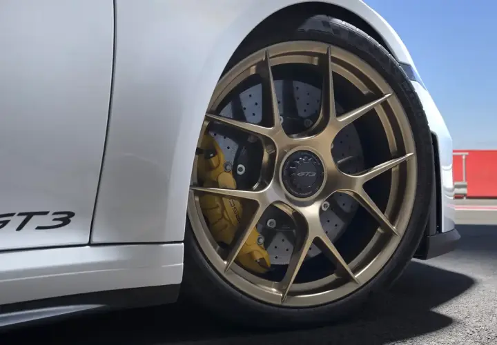Porsche GT3 mit goldenen Felgen und gelben Bremssätteln. Die Keramik Bremsen Kosten sind hoch, aber die Leistung ist unschlagbar.