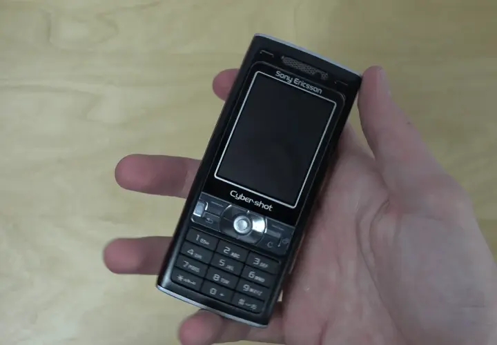 Dłoń trzyma czarny telefon Sony Ericsson k800i z napisem Cyber-shot.