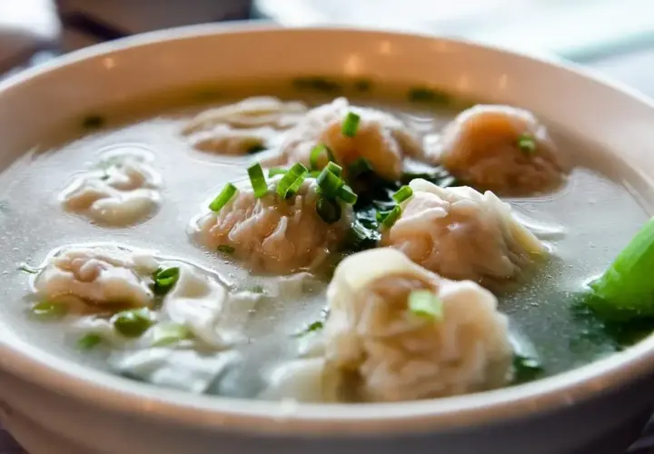 A miseczce paruje aromatyczna zupa won ton, ozdobiona szczypiorkiem.
