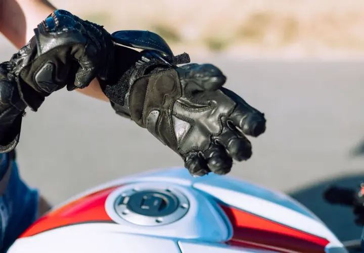 Persona se ajusta guantes de moto negros. Es obligatorio llevar guantes en moto para protegerse.