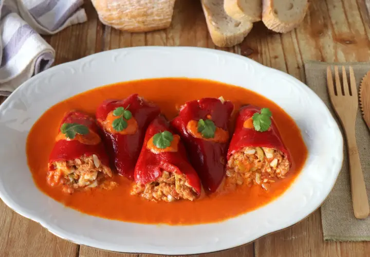 Pimientos del piquillo rellenos de atún y huevo, bañados en una salsa de pimientos. Un plato casero listo para disfrutar.