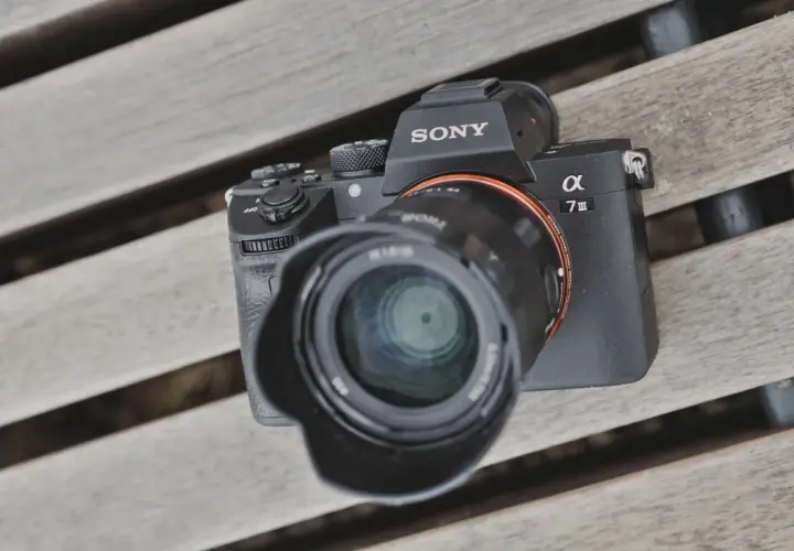 Sony A7 III test na drewnianej ławce. Aparat z obiektywem leży na deski.