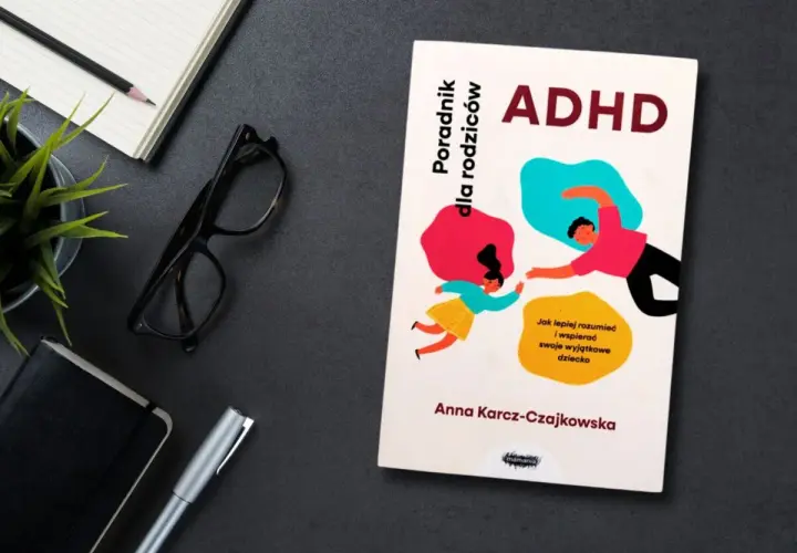 Książka "ADHD. Poradnik dla rodziców" Anny Karcz-Czajkowskiej, z ilustracją rodzica i dziecka. Obok notatnik, okulary i długopis.