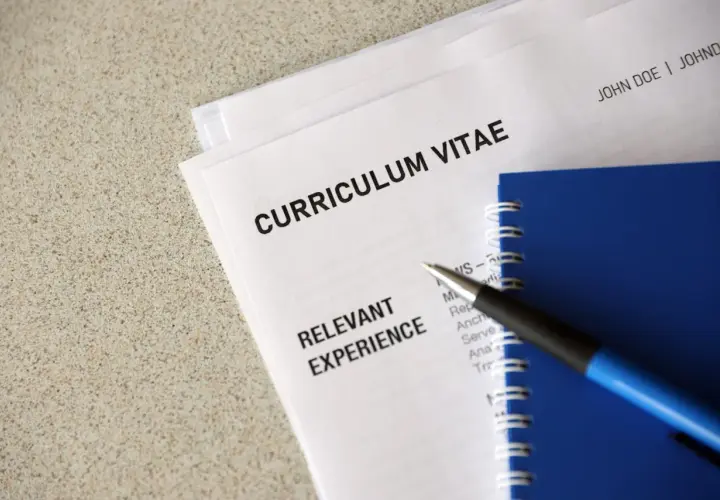 Długopis leży na dokumentach z nagłówkiem "CURRICULUM VITAE" i sekcją "RELEVANT EXPERIENCE". To klauzula CV po angielsku, gotowa do uzupełnienia.