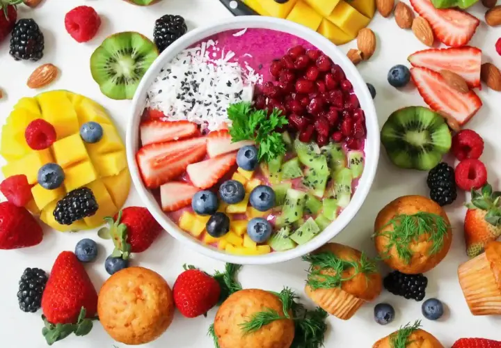 Frukostskål med bär, kiwi, mango och kokos. Muffins och mandlar runt om. En vitaminrik start på dagen!