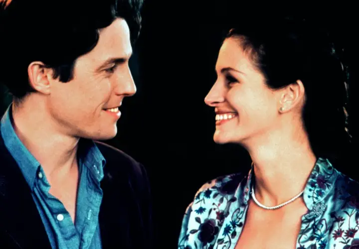 Uśmiechnięta obsada Notting Hill: Hugh Grant i Julia Roberts patrzą na siebie z czułością.