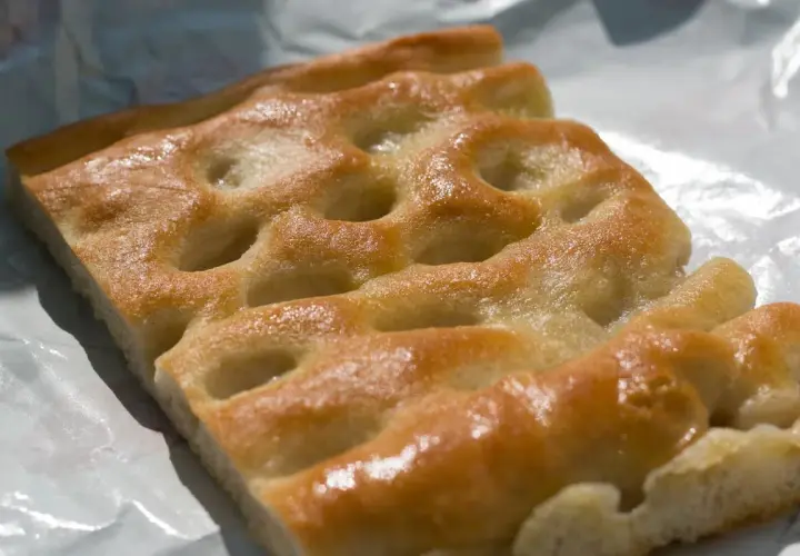 Focaccia genovese, un must per capire cosa mangiare a Genova. Dorata, soffice e profumata, perfetta da gustare in ogni momento.