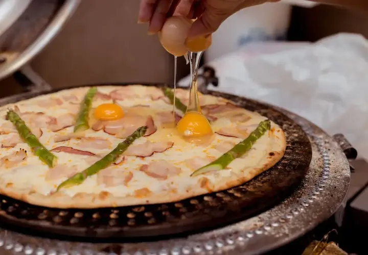 Na pizzę z boczkiem i szparagami dodawane jest jajko.