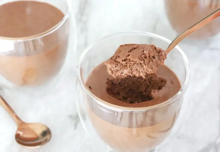 Une cuillère prélève une bouchée aérienne d'une mousse au chocolat onctueuse, parfaite la veille ou le jour même.