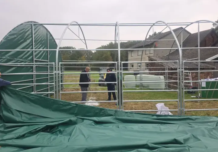 Aufbau einer 100 qm Halle genehmigungsfrei in Bayern. Männer montieren das grüne Dach einer Leichtbauhalle.