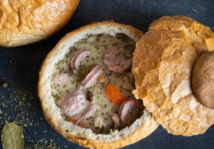 Pyszny żurek z jajkiem i kiełbasą podany w chlebie. Aromatyczne zioła i przyprawy podkreślają smak tradycyjnej polskiej zupy.