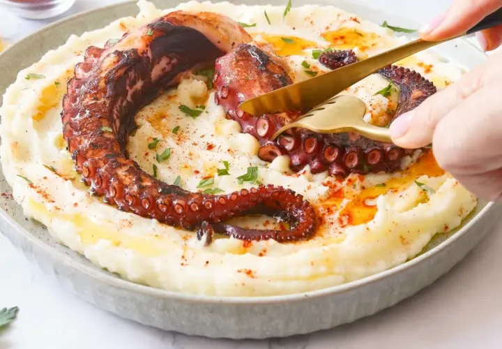 Un delicioso pulpo a la brasa, con sus tentáculos crujientes, servido sobre un puré cremoso.