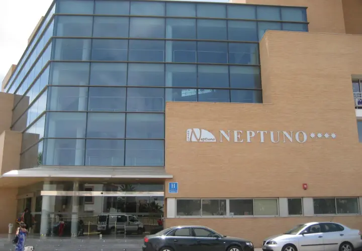 Fachada moderna del hotel Neptuno Roquetas de Mar, con amplios ventanales y detalles en ladrillo.