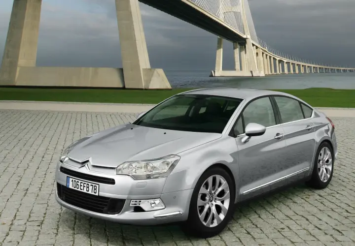 Srebrny Citroen C5 2.0 HDI na tle imponującego mostu wiszącego.