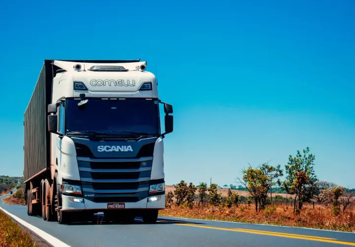 Biała Scania z naczepą jedzie po pustej drodze. Zastanawiasz się, ile ton można załadować na tira?