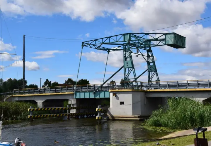 Most czterech pancernych, podnoszony most nad kanałem, z zieloną konstrukcją i błękitnym niebem.