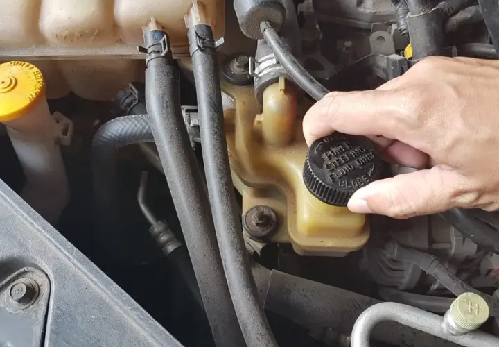 Ręka zakręca korek zbiorniczka płynu wspomagania kierownicy. Wymiana płynu wspomagania to ważny element dbania o auto.