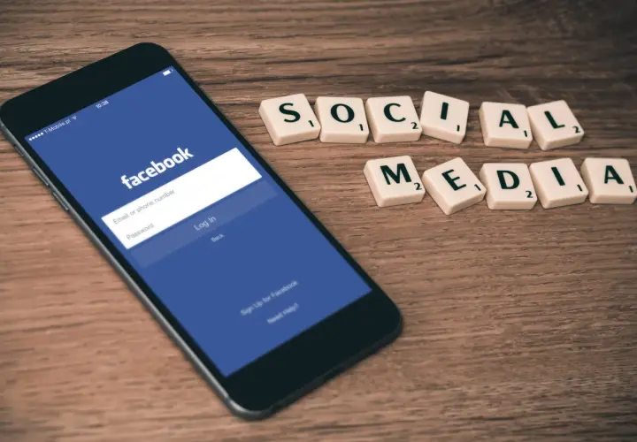 Telefon z ekranem logowania Facebooka i kafelki z napisem "SOCIAL MEDIA". Dowiedz się, jak zmienić email na FB.