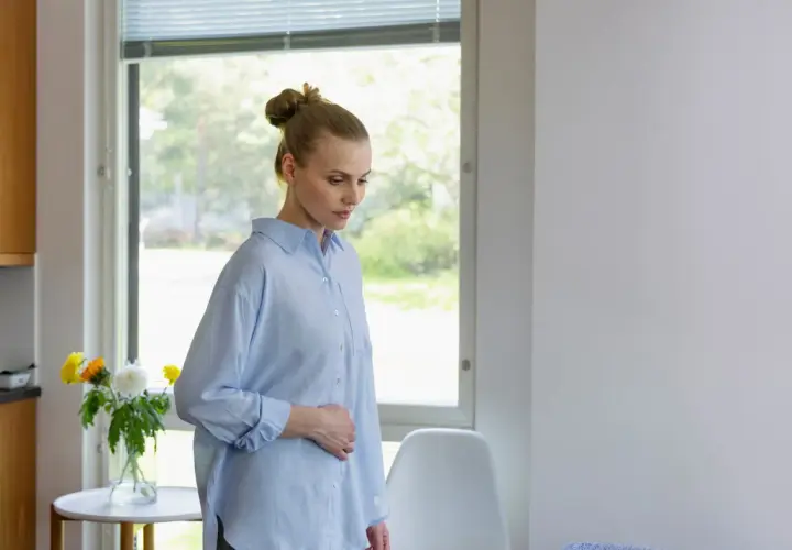 Kvinna med handen på magen, kanske oroande över klamydia symtom.