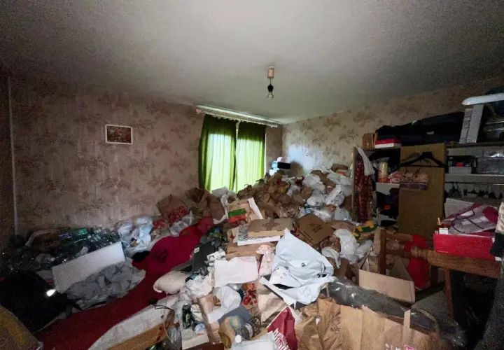 Un logement insalubre envahi par des montagnes de sacs et de détritus. La pièce est encombrée, rendant la circulation difficile.