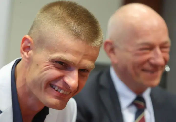 Uśmiechnięty Tomasz Komenda, który otrzymał ogromne odszkodowanie za niesłuszne skazanie, siedzi obok drugiego mężczyzny.