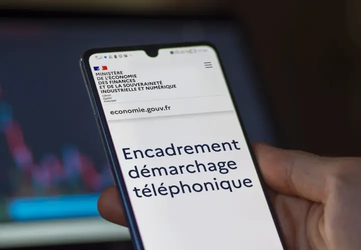 Un smartphone affiche le site du Ministère de l'Économie, avec le titre "Encadrement démarchage téléphonique".