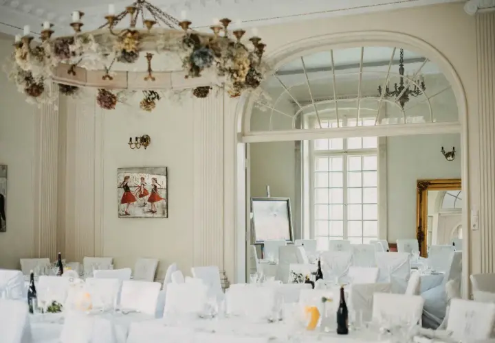 Elegancka sala bankietowa w pałacu Grąbkowo, udekorowana kwiatami i przygotowana na przyjęcie.