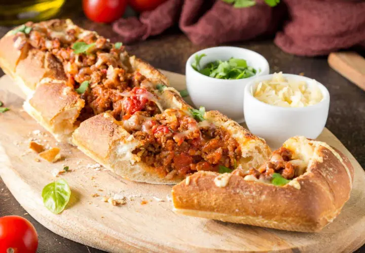 Une baguette farcie généreusement avec une sauce à la viande savoureuse et du fromage fondant, prête à être dégustée.