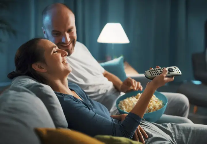 Para spędza miły wieczór, śmiejąc się i jedząc popcorn. Idealny czas na fajne filmy romantyczne na wieczór.