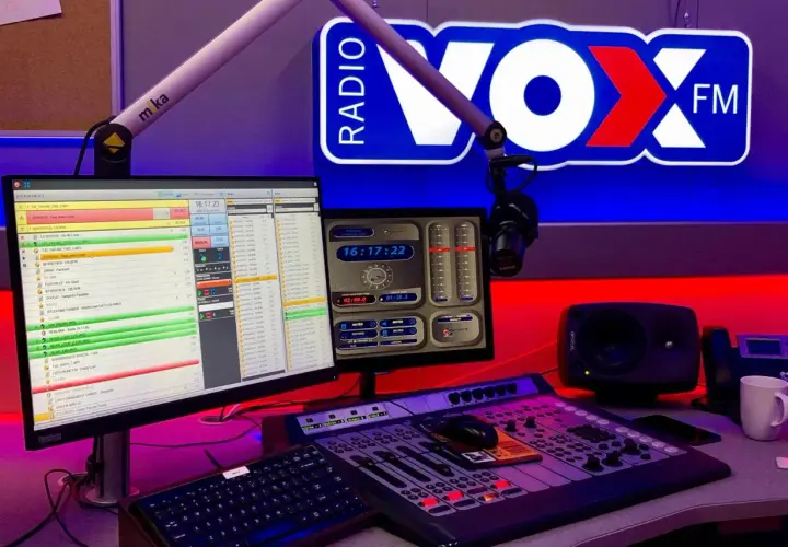 Studio radiowe VOX FM z mikrofonem, konsolą mikserską i monitorami.