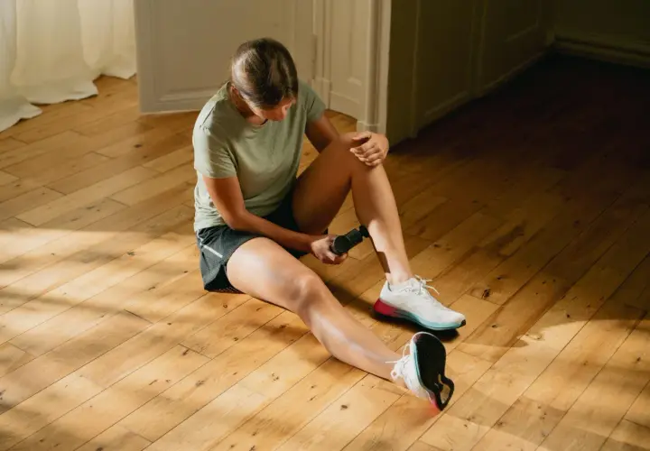 Kobieta wykonuje ćwiczenia rehabilitacyjne na stopę, używając masażera.