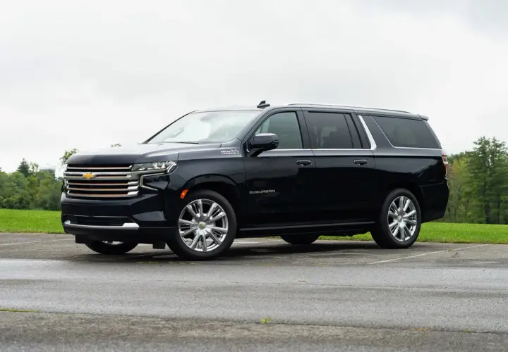 Czarny Chevrolet Suburban High Country z chromowanymi felgami stoi na parkingu.