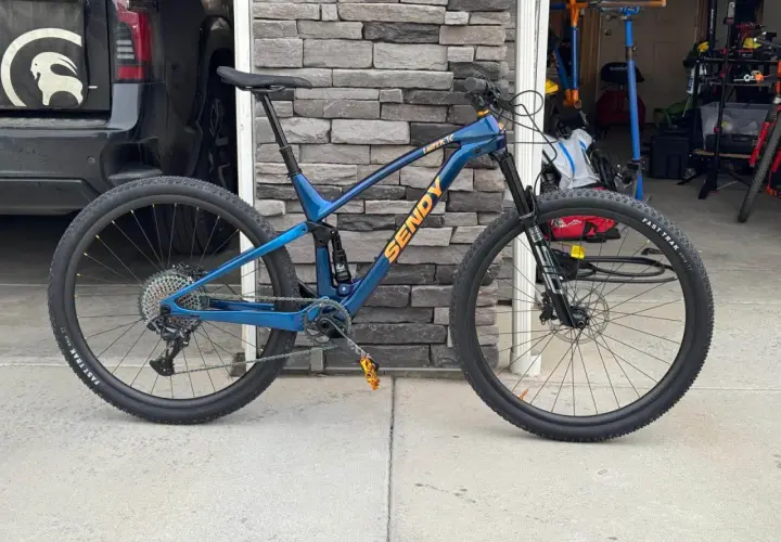 A blue Sendy mountain bike with full suspension, ready for any trail. Its robust mountain bike suspension system promises a smooth ride.