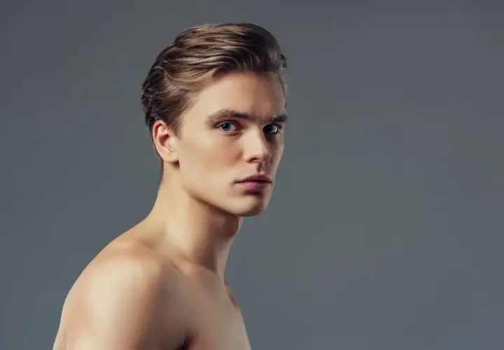 Joven con pelo liso hombre, ojos azules y piel clara, mirando a la cámara con expresión seria.
