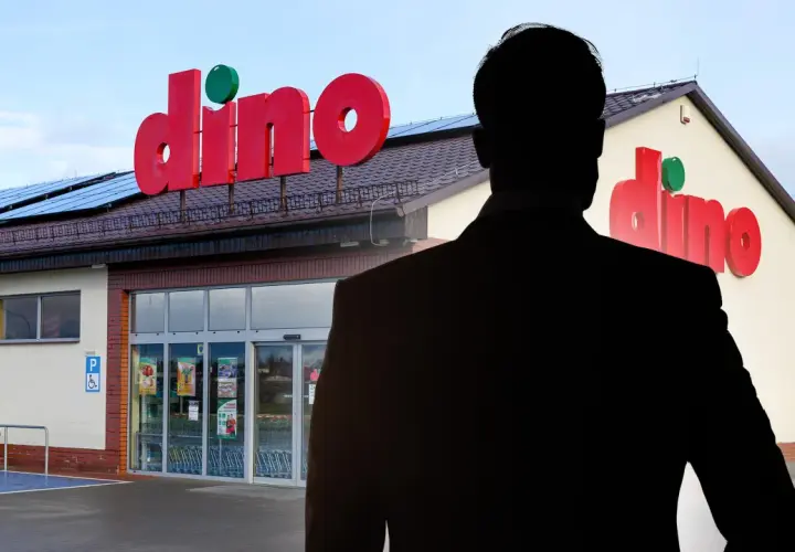 Sylwetka mężczyzny w garniturze na tle sklepu Dino.