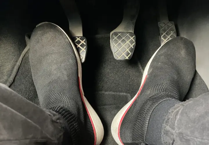 Pies con zapatillas negras listas para arrancar. Hay que pisar el embrague para arrancar el coche.