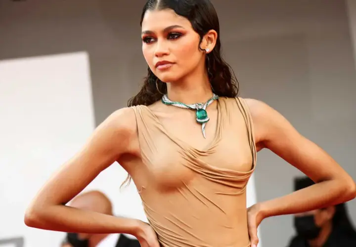 Zendaya med vattenkammat hår, klädd i en beige klänning och en grön ormhalsband.