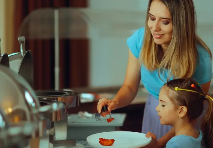 Mama pomaga córce nakładać jedzenie na talerz, stosując zasadę 80/20 diety.