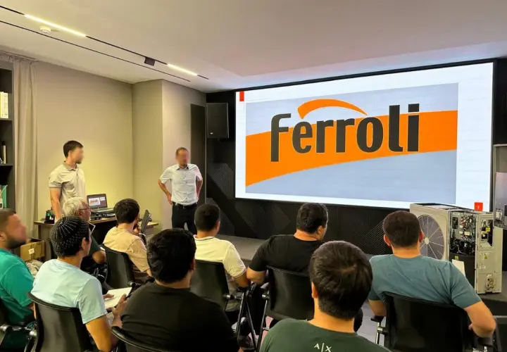 Szkolenie z serwisu Ferroli. Grupa osób słucha prezentacji na tle logo Ferroli. Kontakt do serwisu jest kluczowy.