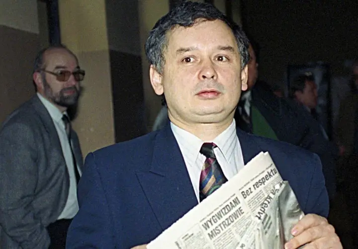 Jarosław Kaczyński z gazetą, zastanawia się, kto ze starej gwardii PiS trafił na "czarną listę". Obok mężczyzna w okularach.