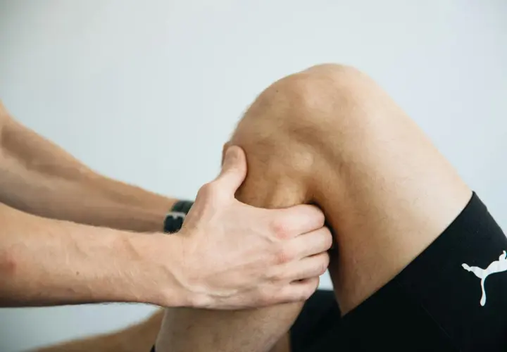 Fizjoterapeuta bada kolano, pomagając zrozumieć, jak wzmocnić więzadła w kolanie.