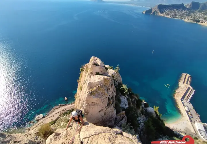 Escaladora en el Peñón de Calpe, con el mar azul y la costa al fondo.
