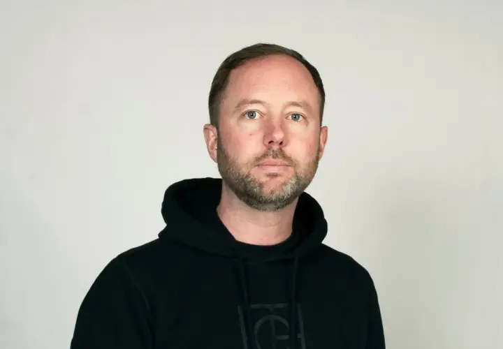 Daniel Holmgren, en man med blå ögon och skägg, bär en svart huvtröja.